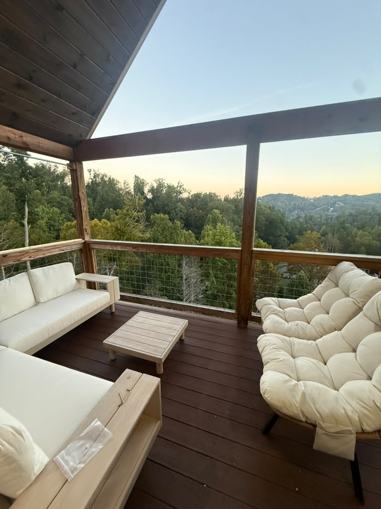 The covered deck at Cedar & Spring at dusk, looking out over wooded ridges